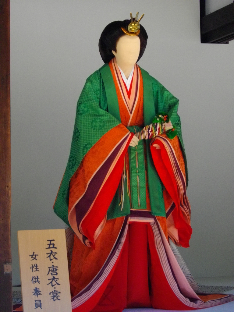 Mannequin dressed in itsutsuginu karaginu mo. There is a hiogi , folded, in the hands held at waist level.