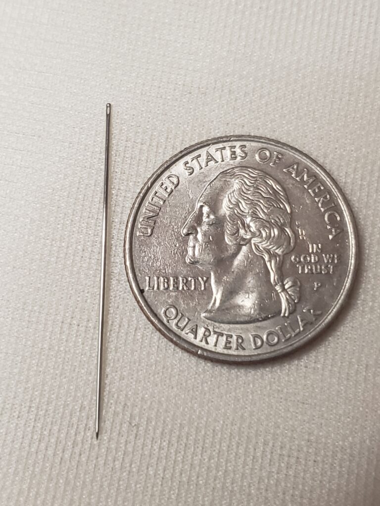 A needle to the left of a quarter.