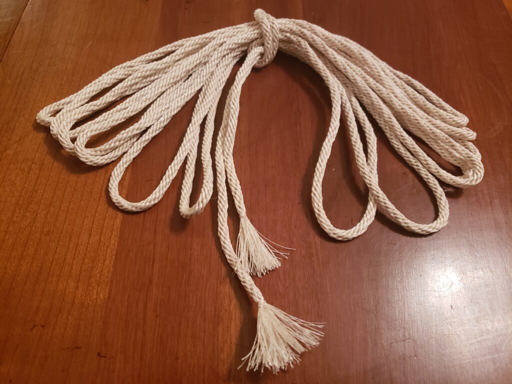 A looped bundle of white braided cord, kumihimo, with tasseled ends.