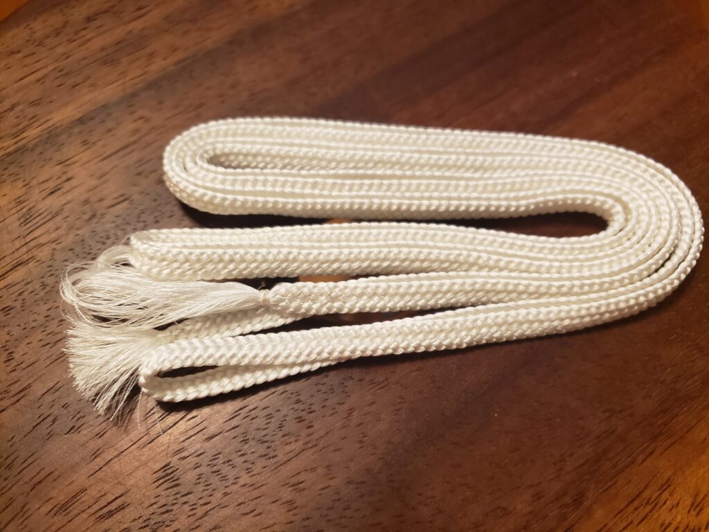 A bundle of flat woven braid folded in half repeatedly The braid texture is similar to flat shoelace braid.