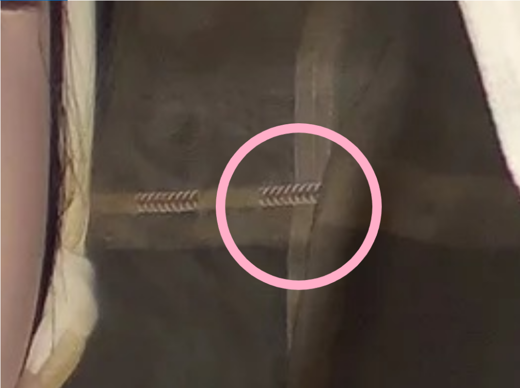 Pink outline of a circle around a cord woven through fabric laying on the viewer's side of the fabric on top of a seam where to pieces are joined.