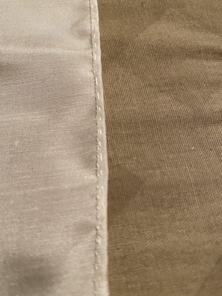 A rolled hem on white silk fabric.