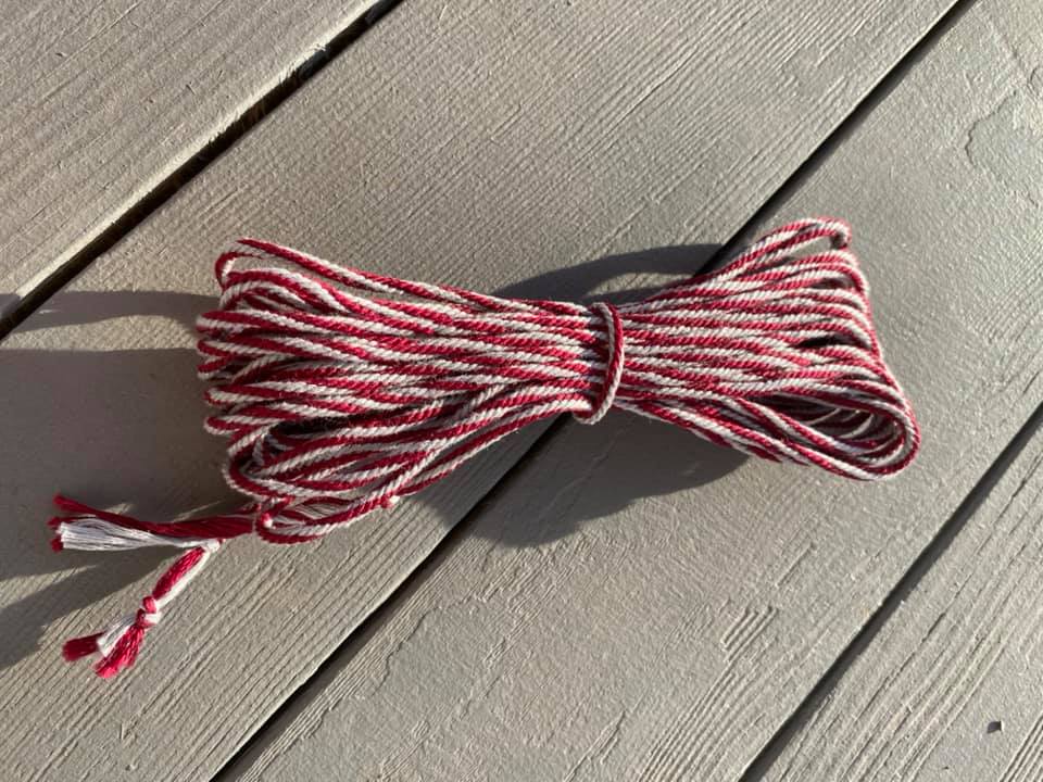 a bundle of marron and grey spiraled braided cord sitting on a darker grey painted wood slat background